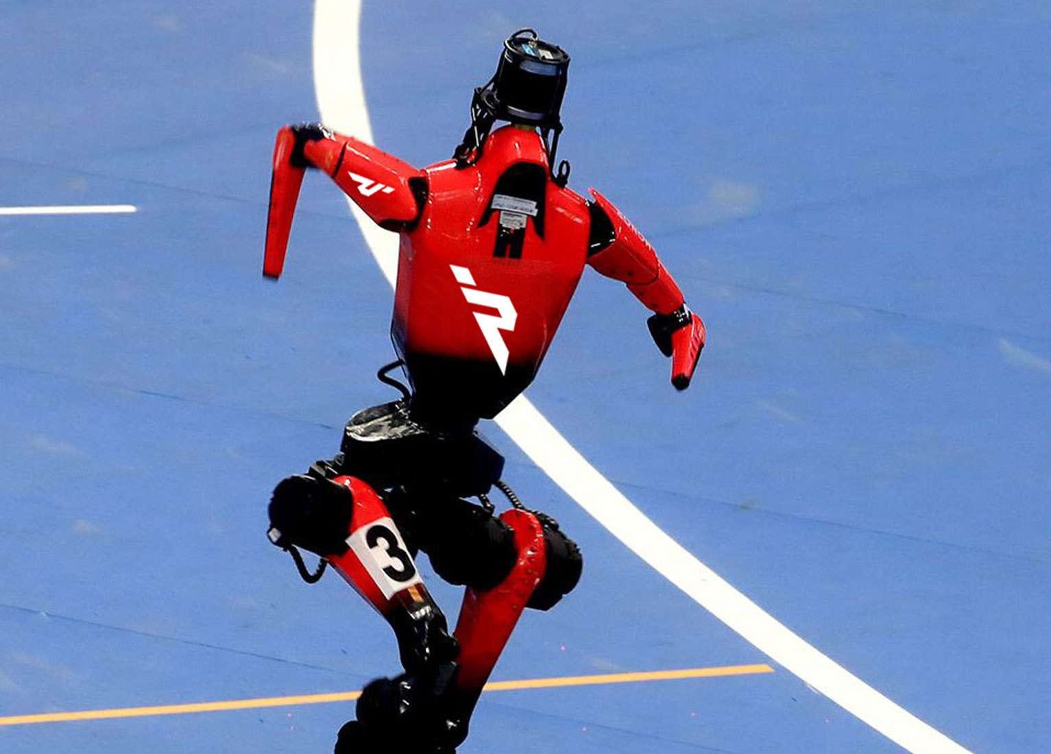 A red humanoid robot racing along a track